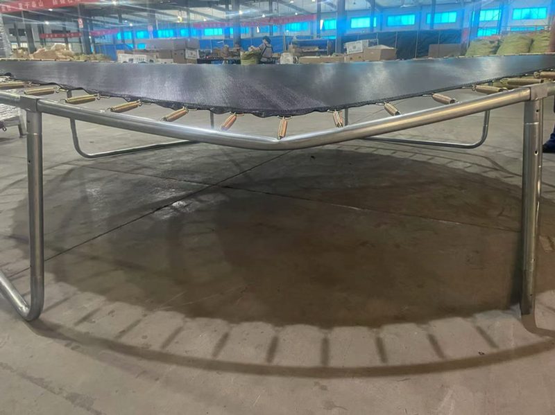 A trampoline frame and mat under static load testing to verify its weight capacity